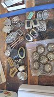 Overview of various vintage jeweled barrettes and hair accessories arranged on a wooden surface, showing different shapes and designs including metal, faux pearls, and rhinestones.