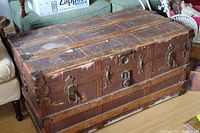 Front and top view of vintage wooden trunk showing brass fittings, locks, and detailed metalwork on the edges and corners