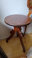 Front view of the vintage solid wood round table showing the round top surface and three curved legs.