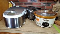Philips HD3095 multi cooker, Crock-Pot slow cooker, and Hamilton Beach toaster arranged on a shelf showing front and side views.