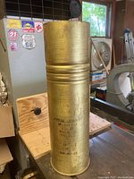 Full exterior view showing the brass casing with military markings and overall shape