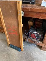 Brookins wooden car creeper leaning upright showing side view and wheels.