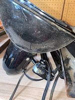 Close-up of black overhead work light showing metal cage around the bulb.