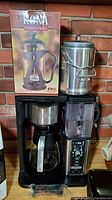 Ninja coffee maker with glass carafe, Kona French press with box, and stainless steel stove top percolator displayed together on countertop.