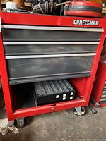 Front view of cabinet showing three drawers and open lower compartment above lockable bottom drawer with casters