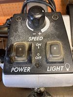 Close-up of control panel showing speed dial, power switch, and light switch of Dremel scroll saw.