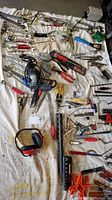 Overview of assorted hand tools, power tools, and accessories laid on a cloth surface.