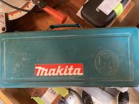 Closed Makita metal carrying case with Makita red and white logo on the lid.