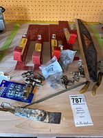 Wide angle photo showing roofing brackets, paint shield, cabinet hinges, assorted plumbing valves, and other hardware on a wooden surface.