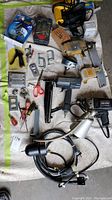 Photo showing full overview of power tools, clamps, hand tools, and hardware supplies spread on floor.