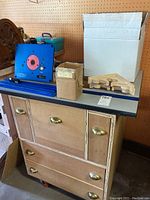 Front view of plywood storage cabinet with brass cup handles and black laminate top
