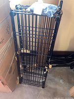 Metal wire grid shelving unit components stacked vertically, showing shelves and hardware bag.