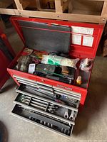 Open red Craftsman top chest with loose items, cable ties and small accessories