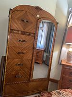Front view of the vintage wood armoire showing the mirrored door and five drawers with metal handles.