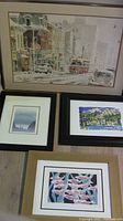 Full view of all four framed prints laid on the floor showing varying sizes and subjects, with one featuring a misty landscape and another an abstract floral arrangement.