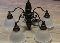Photo shows an antique bronze finish 5-light chandelier with curved arms and frosted glass shades.