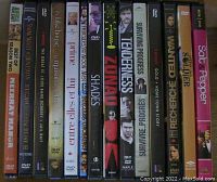 Photo showing spine view of 14 assorted DVDs labeled with various movie titles.