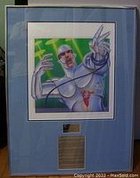 Full frontal photo of the framed print showing the artwork, signature, and numbering with light blue mat and silver frame.