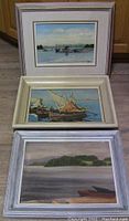Three framed acrylic paintings stacked vertically showing fishing boats and shoreline scenes.