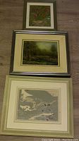Photo of all three framed paintings stacked vertically on carpet showing size and frame details