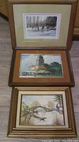 Three framed artworks laid out together, showing two paintings and one print with winter and landscape themes.