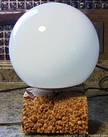 White glass globe lamp on a polished maple burl block base shown from front.