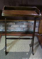 Full view of wooden tray table showing removable tray on folding stand with brass corner accents.