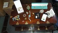 Overview of the lot showing various costume jewelry pieces on wooden surface including watches, earrings, cufflinks and bracelets.