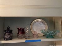 Shelf view showing antique candy dish, glass pitcher, perfume bottle, glass bell, and Limoges plate.