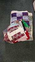 Two folded vintage patchwork quilts stacked, showing different colorful patch patterns including plaids and florals.