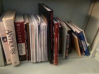 Shelf with multiple reference books focused on antiques, gardening, quilting, and coffee table topics.