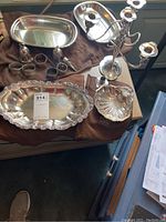 Overview of the lot showing two serving dishes, a five-arm candelabra, two bells, and several napkin rings arranged on a table.