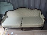 Full front view of vintage Louis XIV style sofa showing wooden frame and cream diamond patterned cushions.