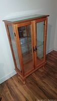 Full view of wood display cabinet showing glass doors and sides, wood frame, and top glass panel