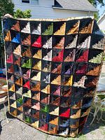 Front of quilt showing colorful geometric patchwork pattern with multiple colors including black, red, blue, green, and tan in a log cabin arrangement.