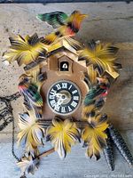 Top view of antique German cuckoo clock showing colorful bird and leaf decorations around clock face