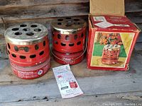 Two Coleman Model 518 heaters side by side on a wooden surface with one original box and instruction sheet included.