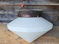 Side view of diamond-shaped milk glass shade with ribbed pattern and metal holder, showing wired connection and condition.