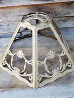 Metal pentagonal lamp shade frame with ornate scroll and shell design, front angle