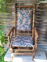 Front and angled views of the Early Victorian platform rocking chair showing the turned wooden frame, armrests, and upholstered cushions with blue and pink paisley fabric.