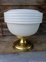 Front view showing the white ribbed glass shade and brass base of the 1930s hall light.