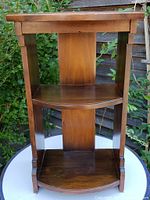 Front view of vintage walnut side table showing two shelves, curved fronts, solid back, and decorative legs