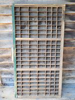 Full view of vintage wooden printer's tray showing multiple small rectangular compartments and green painted edge.