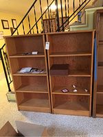 Two matching wooden bookcases side by side, each with multiple shelves. The bookcases have a honey oak finish and seem structurally sound.