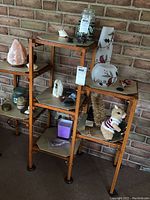 Photo of wooden display stand against brick wall with salt lamp, candles, animal figurines including a Christmas squirrel in a sweater.