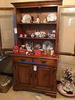 Full view of the young republic china cupboard with contents on shelves and drawers and cabinet below.
