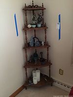 Full view of wooden corner shelf with multiple decorative items arranged on four tiers.