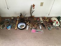 Wide shot showing all stained glass panels, bird and butterfly decorations, dreamcatcher, garden and home items including clippers, back scratcher, and power strips spread on carpet floor.