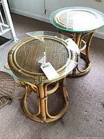 Photo showing two round bamboo tables with oversized clear glass tops on a carpeted floor.