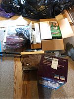 Lot contents on floor with cardboard boxes containing vacuum cleaner accessories, Eureka and Oreck XL vacuum parts visible.